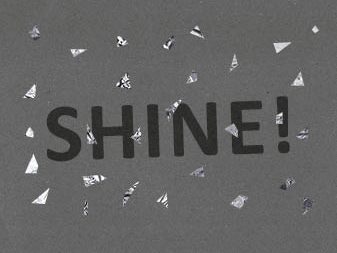 Das Wort "Shine" auf Sonderpapier mit silbernem Konfetti